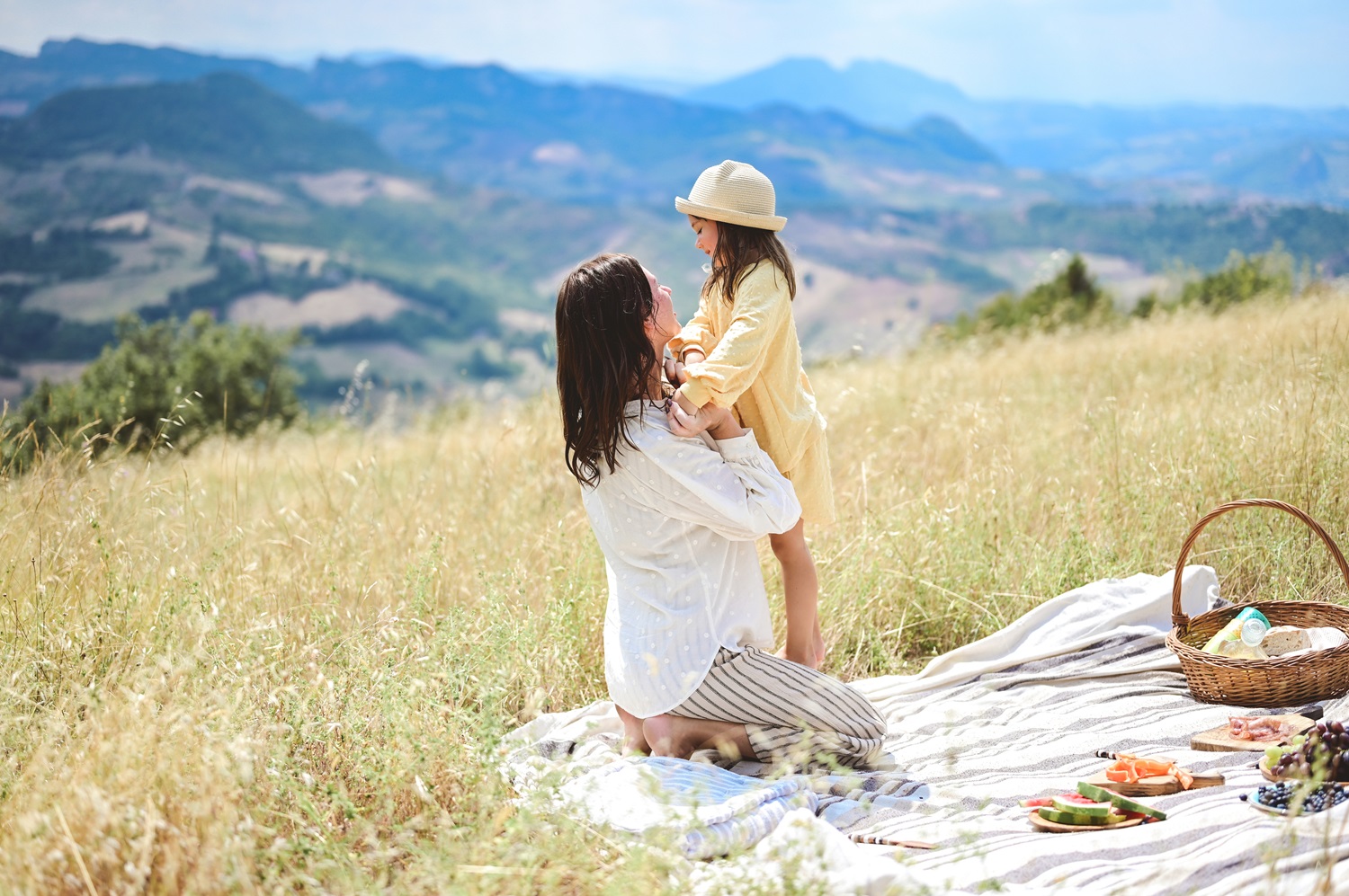 Mother embracing daughter on a picnic outdoors in Hills.
