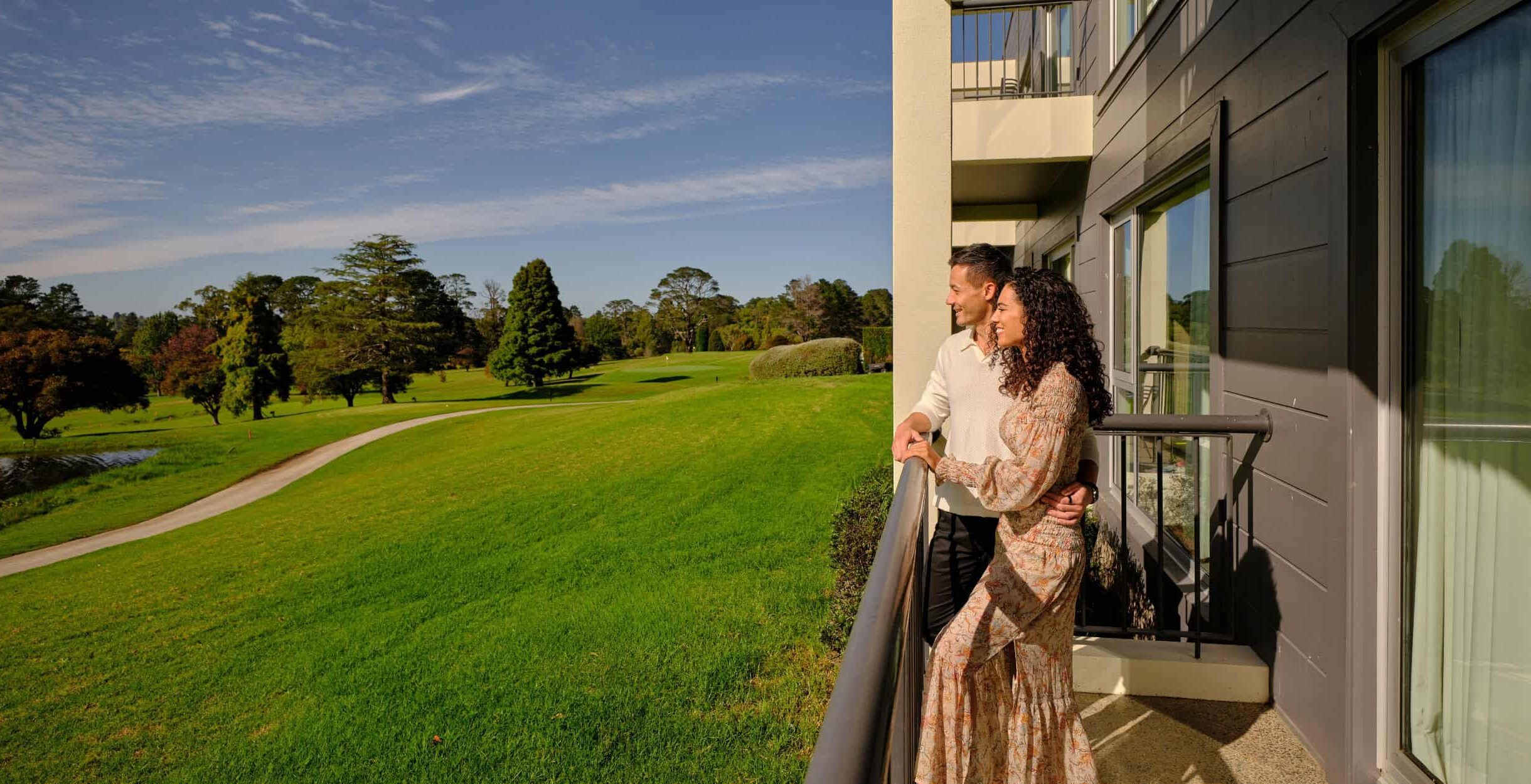 Lady and man enjoying the view of the Gibraltar Golf Course from the balcony of a room at Park Proxi Gibraltar Bowral